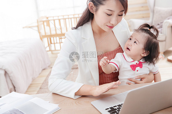 年轻妈妈抱着孩子使用电脑图片