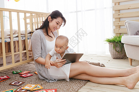 可爱的男孩儿子年轻妈妈在家边看孩子边使用电脑图片