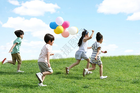 男孩拿着气球快乐的孩子们在草地上玩耍背景
