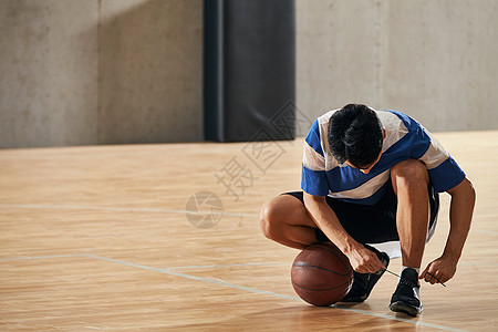 青年男人在篮球场上系鞋带图片