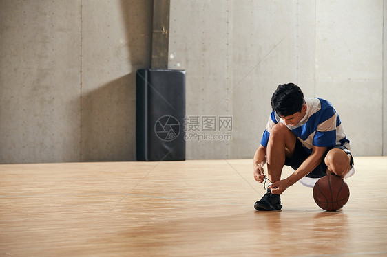 青年男人在篮球场上系鞋带图片