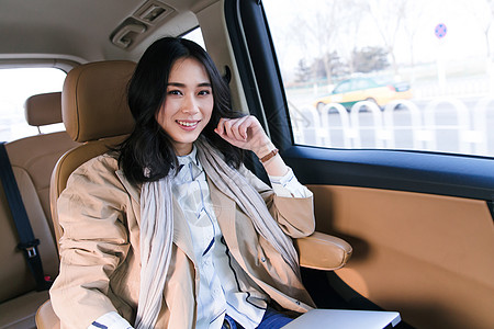 信心着装得体微笑商务女人坐在汽车后座图片