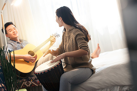 爱愉悦女人快乐情侣在家演奏乐器图片