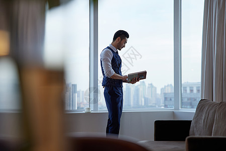 高端商务男士站在窗前看书图片