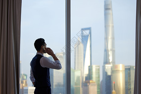 站在窗边打电话的成熟男性背影图片素材