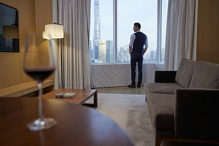 房间里站在窗前的成功商务男性背影图片
