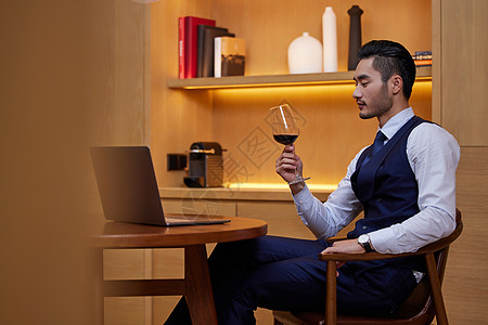 坐在餐桌前喝红酒的男性图片
