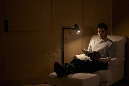 夜晚在沙发上看书的成熟男性图片
