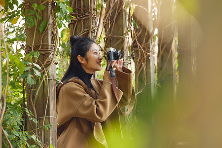 年轻女性公园里拿相机拍照图片