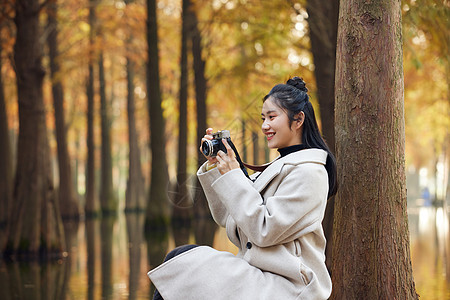 户外美女拿相机拍秋冬风景图片