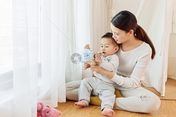 年轻妈妈陪孩子窗边玩耍图片