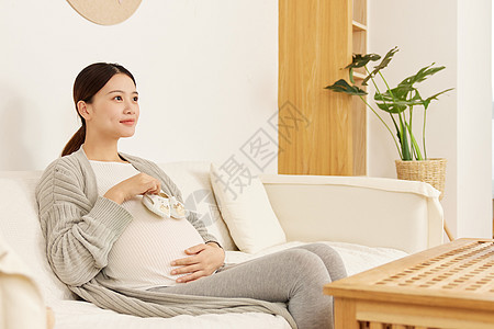 手拿宝宝鞋子充满期待的孕妈背景图片