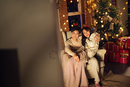 圣诞节夜晚气球堆叠坐着幸福甜蜜的年轻伴侣坐在沙发上背景