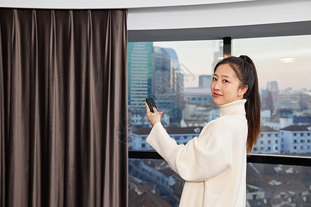 居家女性使用遥控开窗帘形象图片