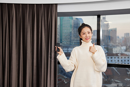 女性使用遥控操作智能窗帘点赞手势图片