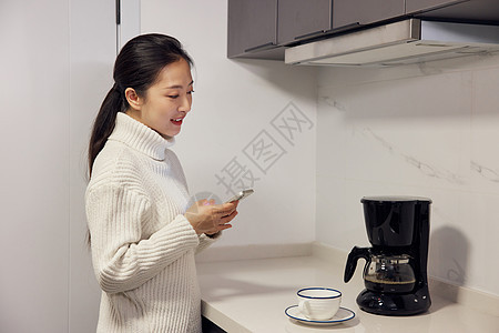 居家女性使用手机操作智能咖啡机图片
