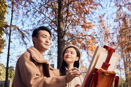 秋季户外情侣在公园的树林里画油画图片