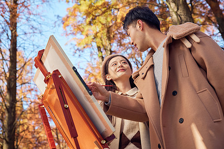 秋季户外情侣在公园的树林里画画图片