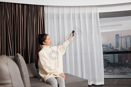 居家女性使用遥控开窗帘形象图片