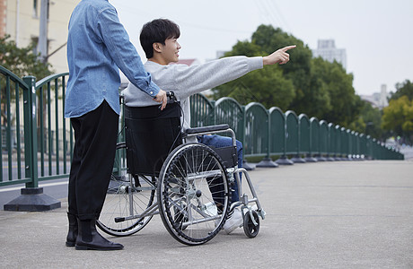 家人陪伴坐轮椅的青年男性外出背景图片