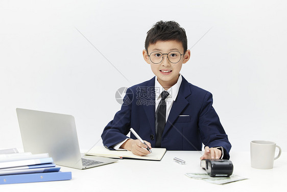小男孩模仿大人坐在办公桌前认真工作图片