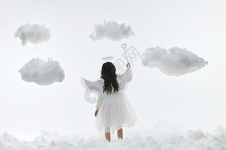 可爱天使小女孩站在云层中举起魔法棒的背影高清图片