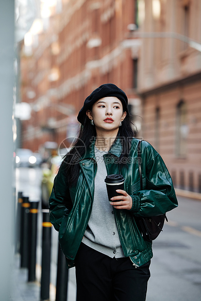 手拿咖啡行走街头的青年女性图片