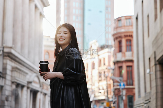 街头手拿咖啡的时尚女性图片