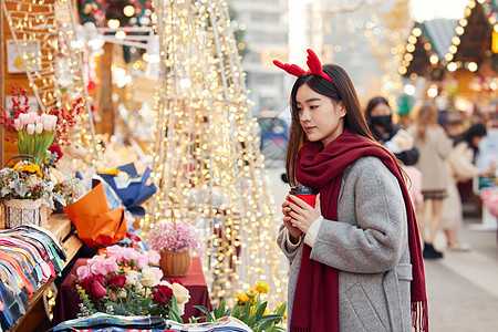 年轻女性手拿咖啡逛市集图片