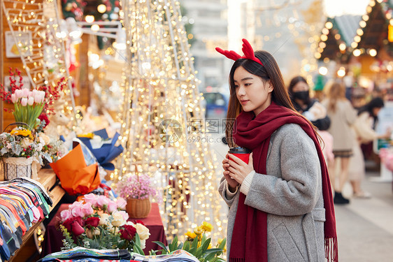 年轻女性手拿咖啡逛市集图片