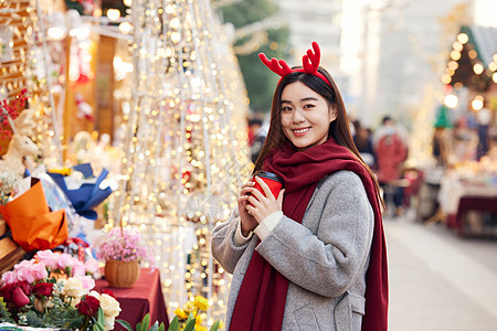 手捧咖啡的冬日女性逛圣诞市集图片