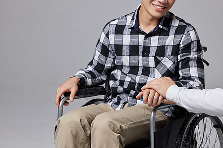 关爱腿部受伤坐轮椅的男性特写图片