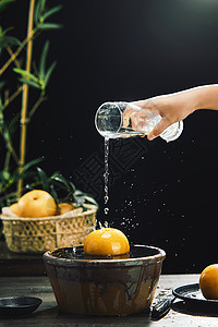 手拿水杯将水倒在秋月梨上洗净图片