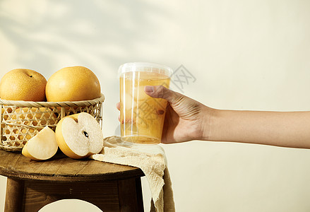 茶几上的水果手拿起木凳上的秋月梨汤背景