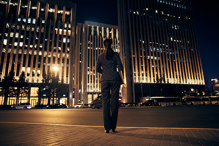 忙碌背影夜晚站在办公楼前的都市职场女性背影背景