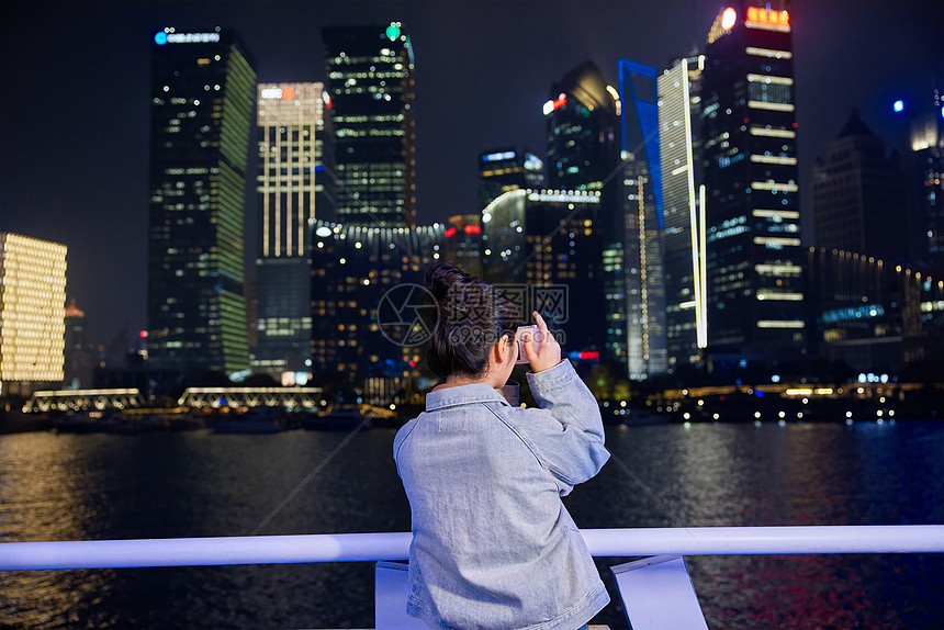 游轮上用相机拍下夜景的旅游女生图片