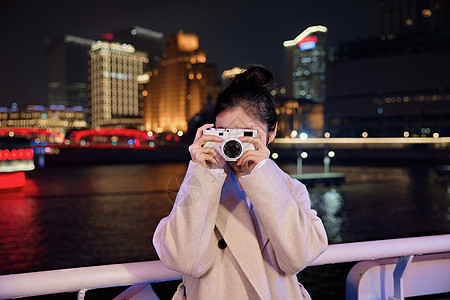 夜晚在游轮船上用相机拍照的旅游女生图片