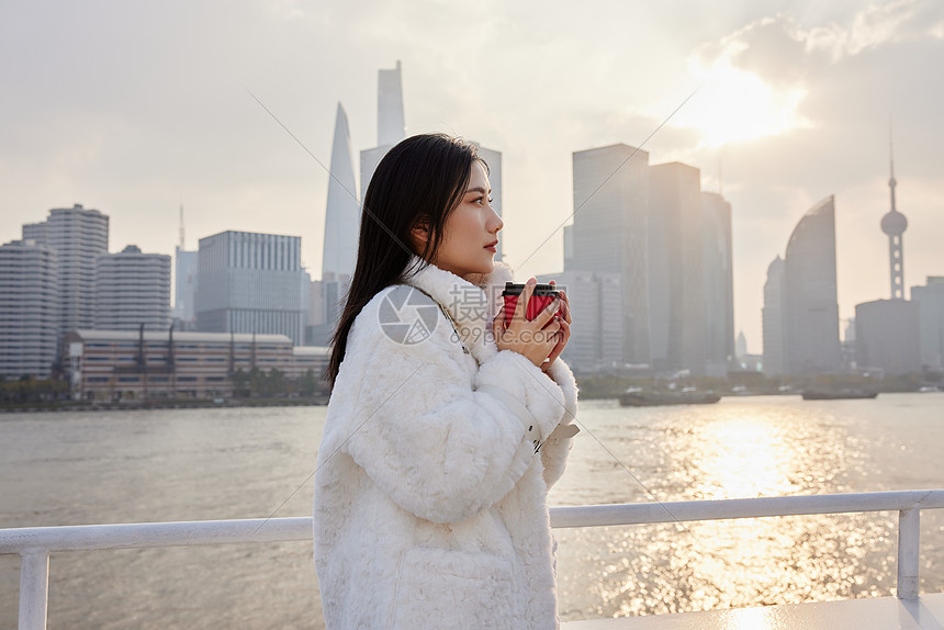 江边阳光下拿着咖啡的女生图片