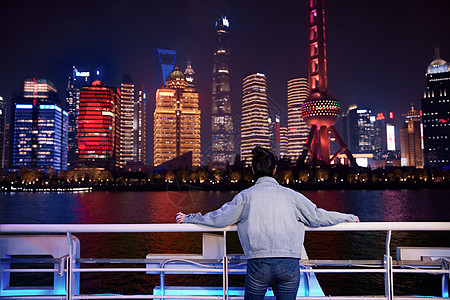 游轮上欣赏城市夜景的女生背影图片