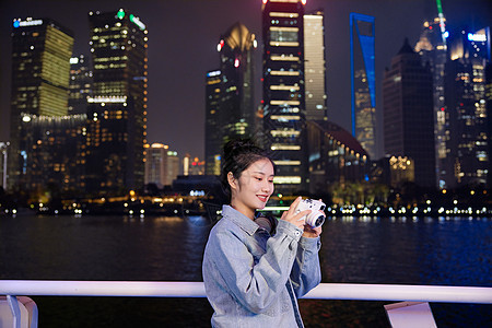 夜晚在游轮船上用相机拍照的旅游女生图片