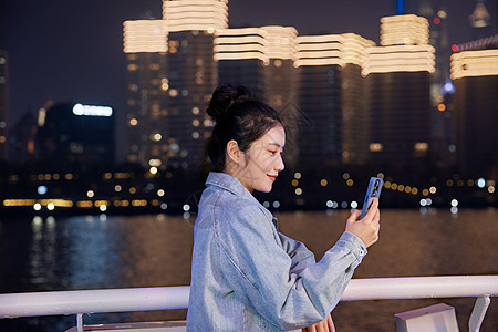 夜晚在游轮船上用手机自拍的旅游女生图片