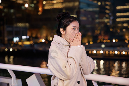 夜晚在游轮船上搓手取暖的旅游女生图片