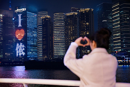 夜晚在游轮船上用手比爱心的女生背影图片