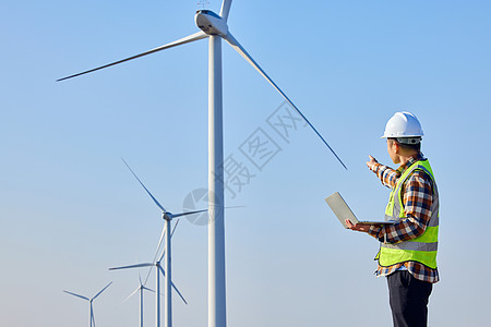 男性工程师检查风力发电设备背影图片