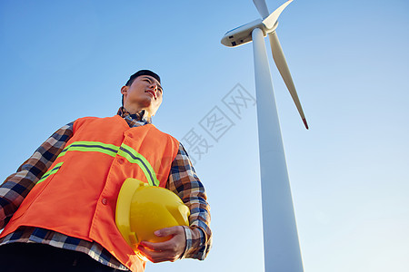 仰拍男性工程师在大风车下形象图片