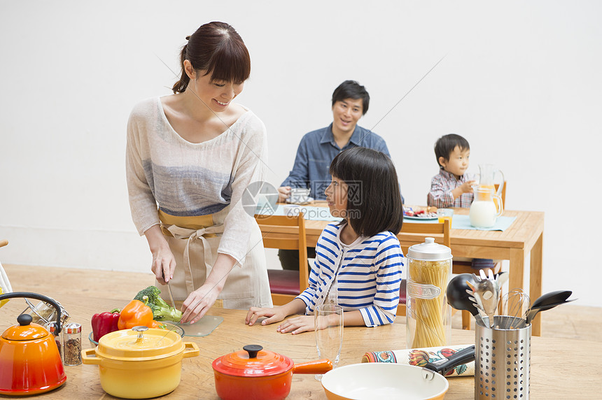 年轻妈妈在切菜和小女孩说话图片