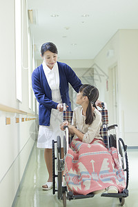 医院走廊上的女护士和轮椅上的小女孩图片