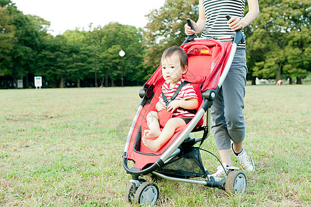 公园散步推宝宝家长在公园推着婴儿车里的宝宝背景