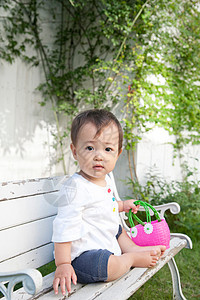 婴儿坐在花园的长凳上图片