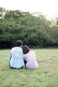 情侣坐在公园草地上的背影图片